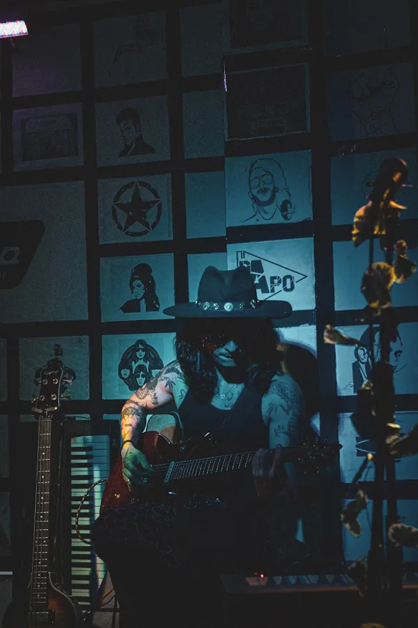 Guitarrista tocando bajo la luz azul de un bar